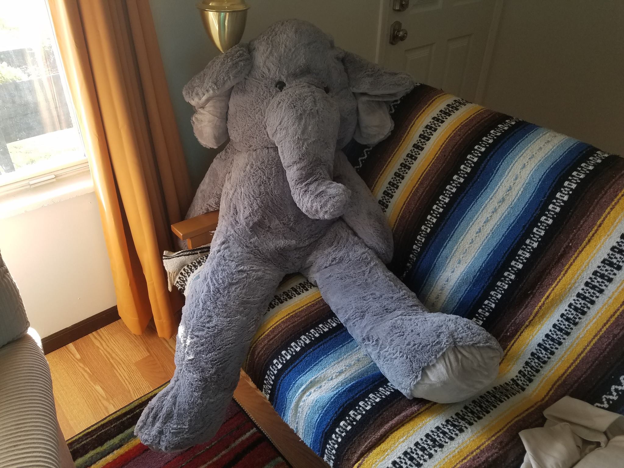 Giant stuffed elephant sprawled across a sofa