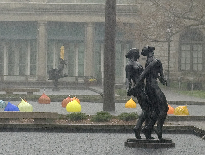 Missouri Botanical Garden main pond area, with statues and colorful globes in water, and heavy rain falling. Moody.