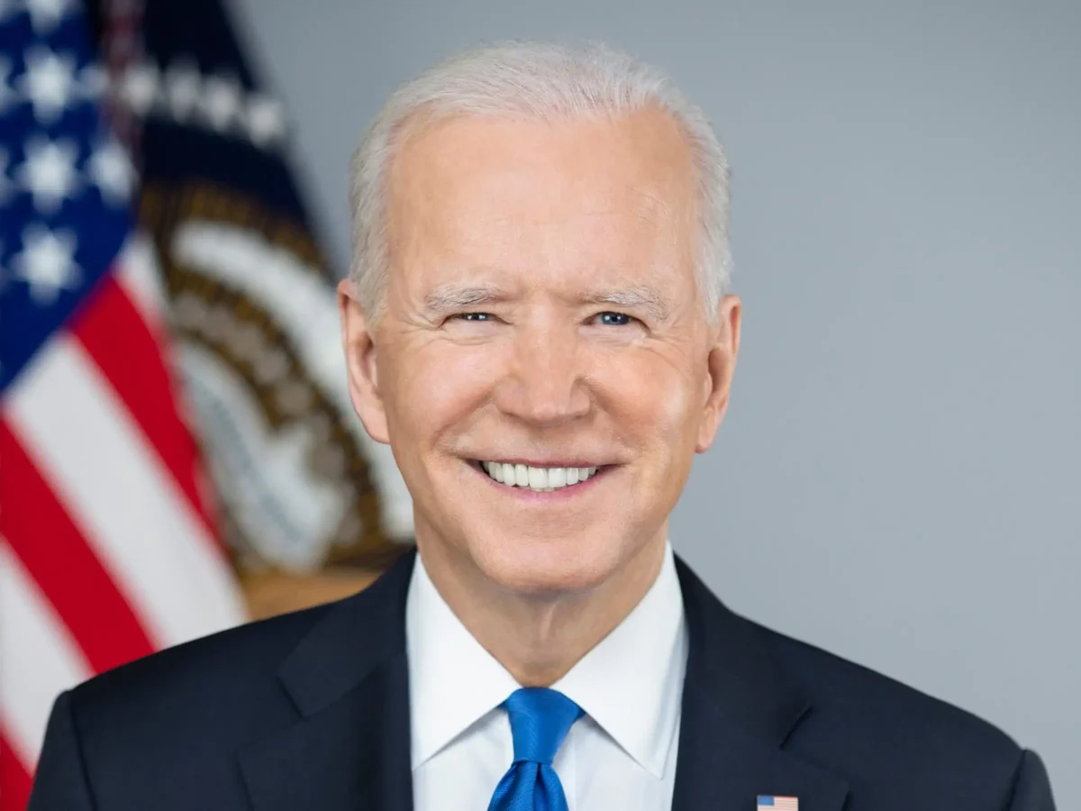 Joe Biden head shot him smiling US flag behind him