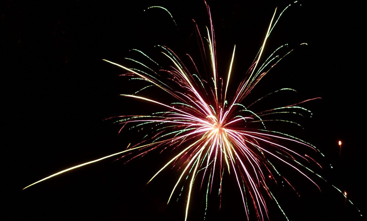 red, green, and white fireworks explosion against black sky