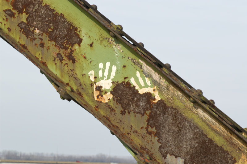 White paint hands on a rusted green steel bridge girder